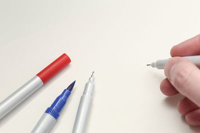 Cropped image of hand holding pen against white background