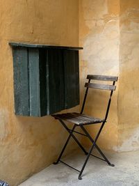 Empty chair against wall of old building