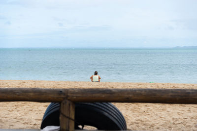 Rear view of man looking at sea against sky