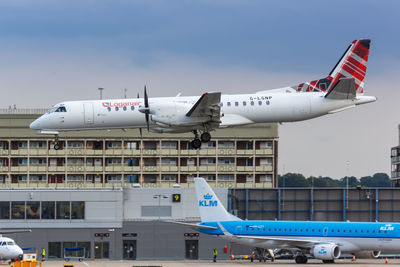 Airplane flying over airport runway against sky