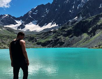 Man standing at lakeshore against mountains