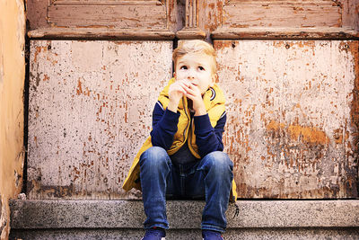 Portrait of boy sitting against wall