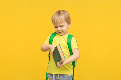 Boy standing against yellow background