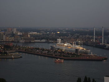 High angle view of illuminated boats sailing in river by city against sky