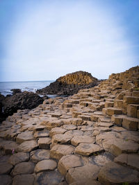 Stone wall by sea against sky