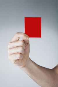 Close-up of hand holding red light over white background