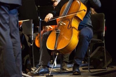 Low section of man playing cello on stage