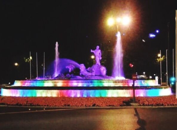 illuminated, night, long exposure, street light, motion, lighting equipment, light trail, glowing, light - natural phenomenon, speed, blurred motion, street, light beam, sky, building exterior, fountain, road, multi colored, city, outdoors