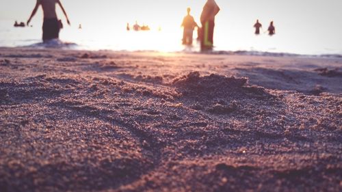 People in sea against sky during sunset