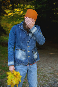 Portrait of a handsome man in casual clothes standing in the park against the background of