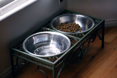 High angle view of pet food in metal bowls on hardwood floor