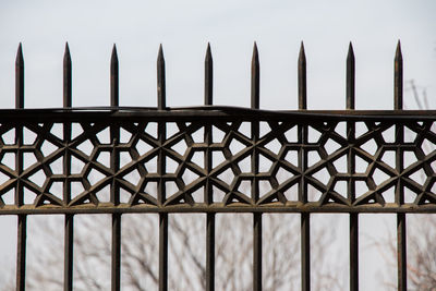 Low angle view of metal fence against sky