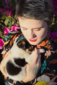 Close up woman with haircut holding puppy in garden portrait picture