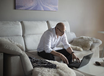 Mature man using laptop on sofa at home during quarantine of coronavirus covid-19