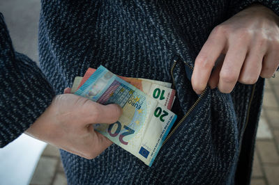 Midsection of woman holding paper currency