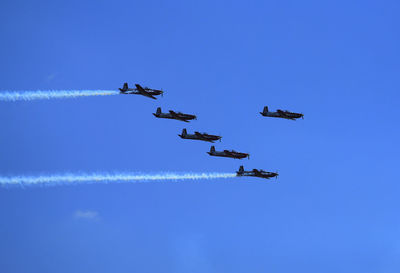 Low angle view of airplanes flying against sky