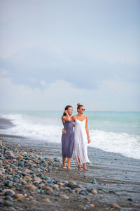 Full length of women standing on beach against sky