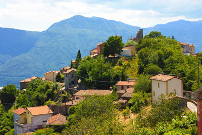 Houses by trees and mountains against sky