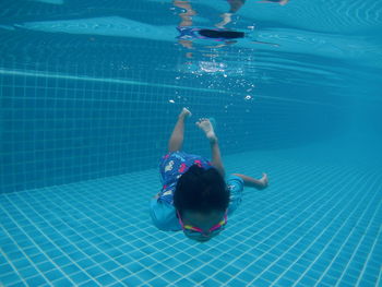 Rear view of boy swimming in pool