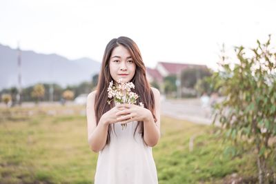 Portrait of a beautiful young woman standing against white wall
