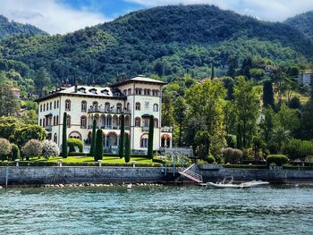 Buildings by river against mountain