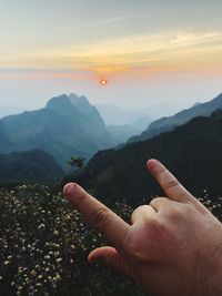Person on mountain against sky during sunset
