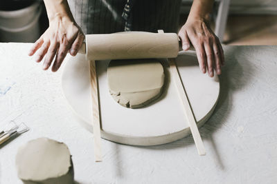 Female owner rolling clay at table in ceramics store