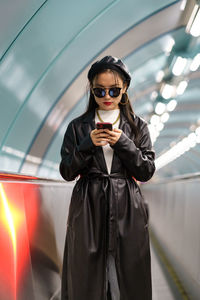 Young lifestyle blogger korean girl posting to social media ride escalator from underground station