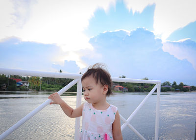 Lovely adorable charming asian little girl standing near meaklong river with blue sky background.