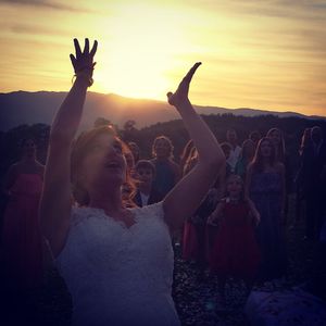 Bride throwing bouquet at wedding reception during sunset