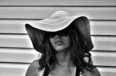 Portrait of beautiful woman wearing hat against wall