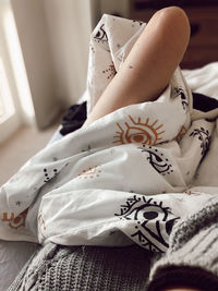 Midsection of woman sitting on bed at home