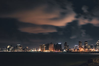 Illuminated buildings in city against sky at night