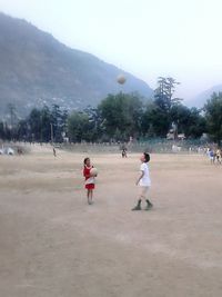 Children playing on mountain against clear sky