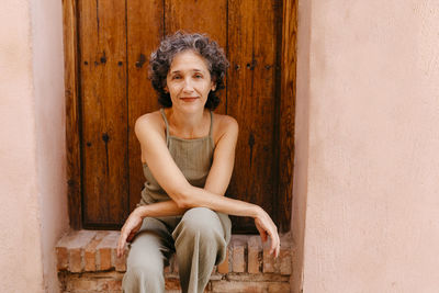 Woman sitting against wooden door on doorway