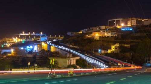 Light trails on street against sky at night