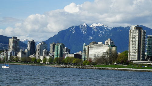 Sea by buildings in city against sky