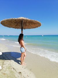 Full length of woman on beach against clear sky