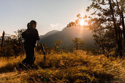 Man standing on field against sky during sunset