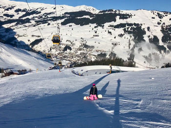 Woman kneeling on snowcapped mountain while snowboarding