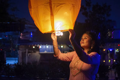 Indian girl celebrating diwali by releasing sky lantern into the sky as part of a ritual 