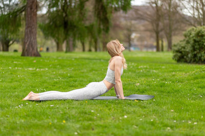 Side view of woman sitting on grassy field