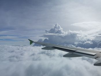 Airplane flying over clouds against sky