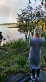 Rear view of woman standing by lake against sky