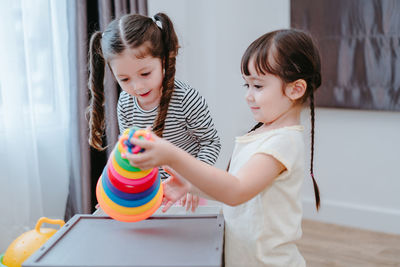 Sisters playing with multi colored toys at home