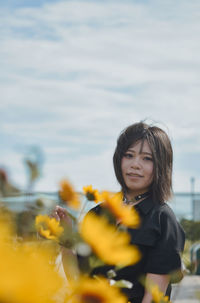 Portrait of smiling woman standing on yellow flowering plants