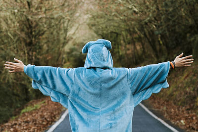 Rear view of person with umbrella standing on road