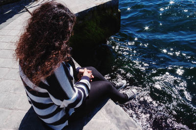 Rear view of woman sitting by sea