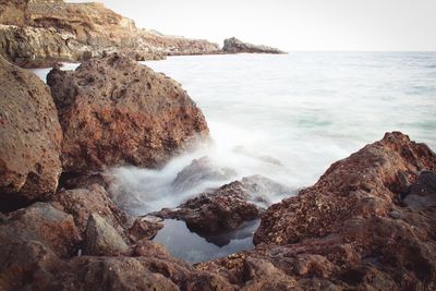 Scenic view of rocks in sea against sky