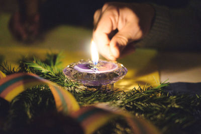 Close-up of hand holding lit candle